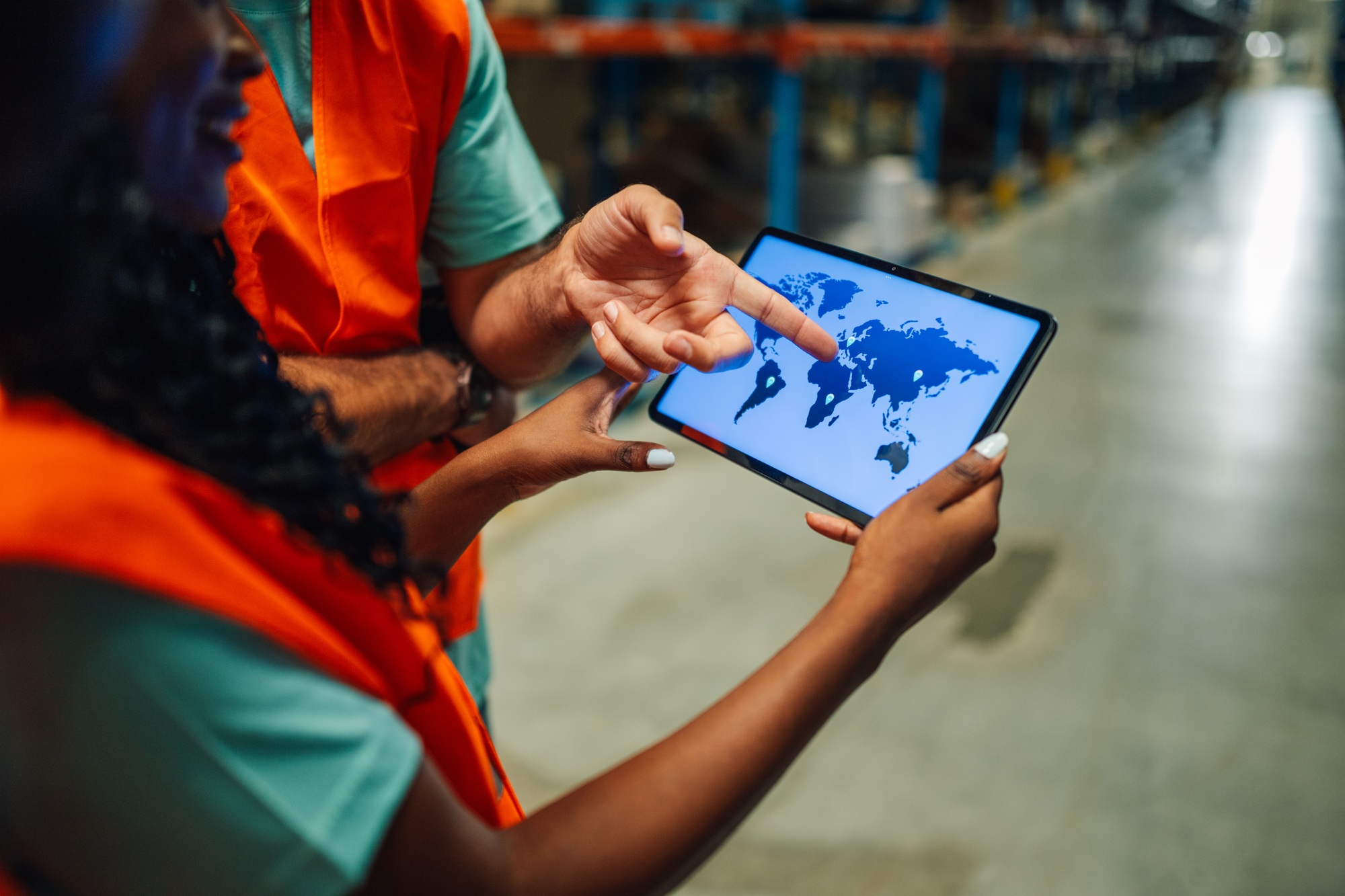 Warehouse workers using digital tablet showing world map for logistics and delivery
